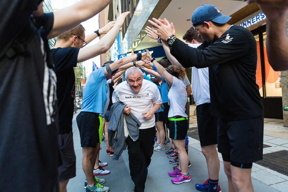 Back on My Feet member running through celebratory tunnel of high-fives